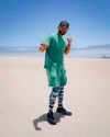 Will Smith wearing Fitbit Charge 4, green shorts, a green shirt and camouflage leggings, takes a boxing stance in the sand dunes.