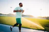 Will Smith running on a track, wearing green running shorts and shirt, and Fitbit Charge 4.