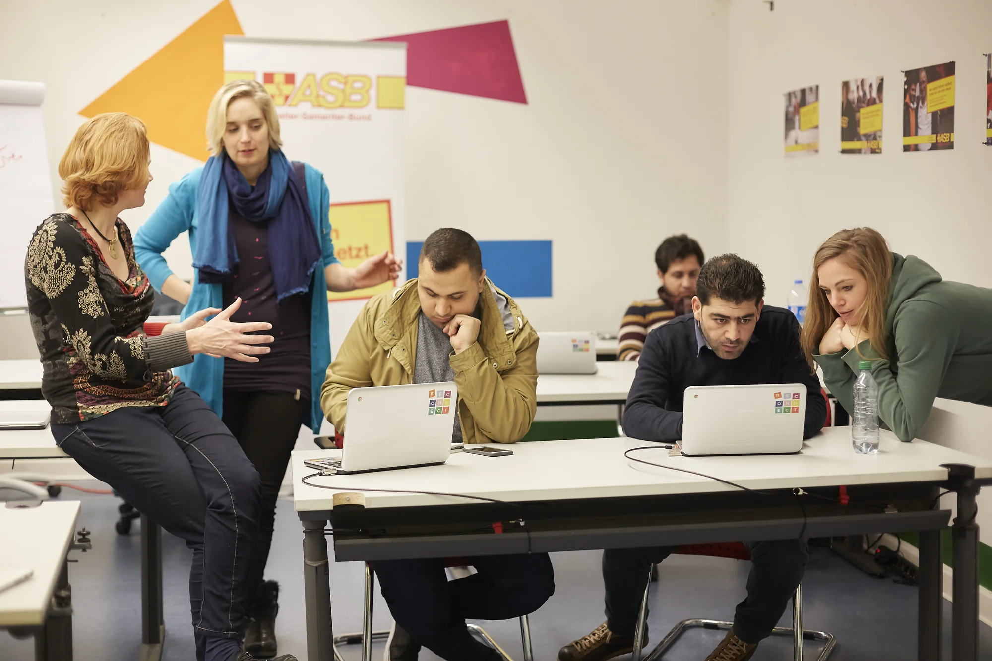 Foto, das mehrere Personen zeigt, die in einem Internet Café vor Chromebook-Laptops sitzen.