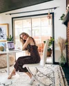 Andi sits at her laptop in her LA home office, wearing a brown-and-white print sundress.