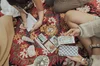 People seated in a circle on a red print carpet around Tarot cards and crystals.