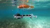 A photo of an underwater perception system, showing an apparatus of pipes, camera and floating devices hovering above a seagrass meadow.