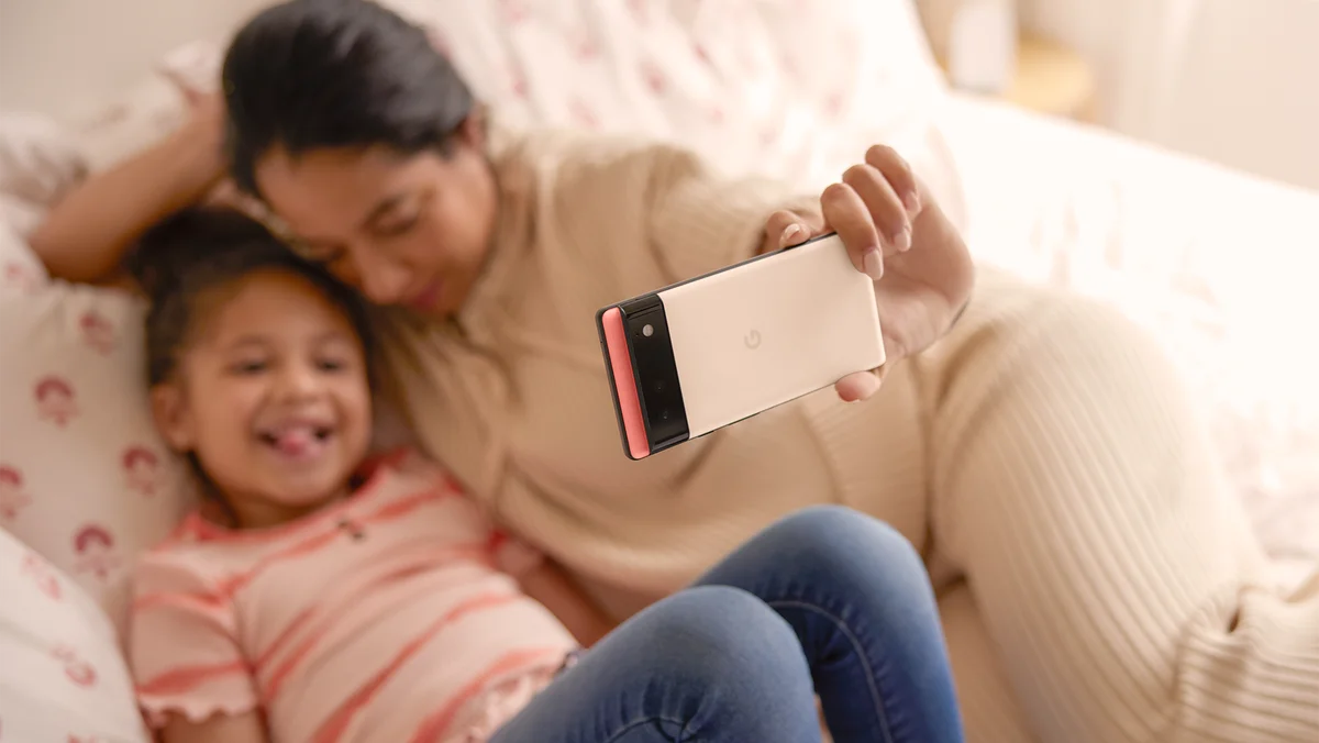 Mother and daughter taking a selfie on a couch.