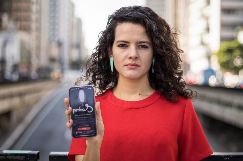 This is a photo of a woman holding up a phone in front of a street.