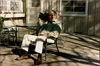 Author's grandfather sits on am outdoor bench with a camcorder over his shoulder.