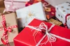 A pile of red and white holiday boxes are wrapped in a variety of gift wrapping and bows.