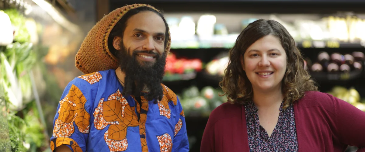 Two people standing next to each other inside Gem City Market, a grocery store