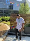 Grant standing in front of Google sign at headquarters holding his Intern hat.