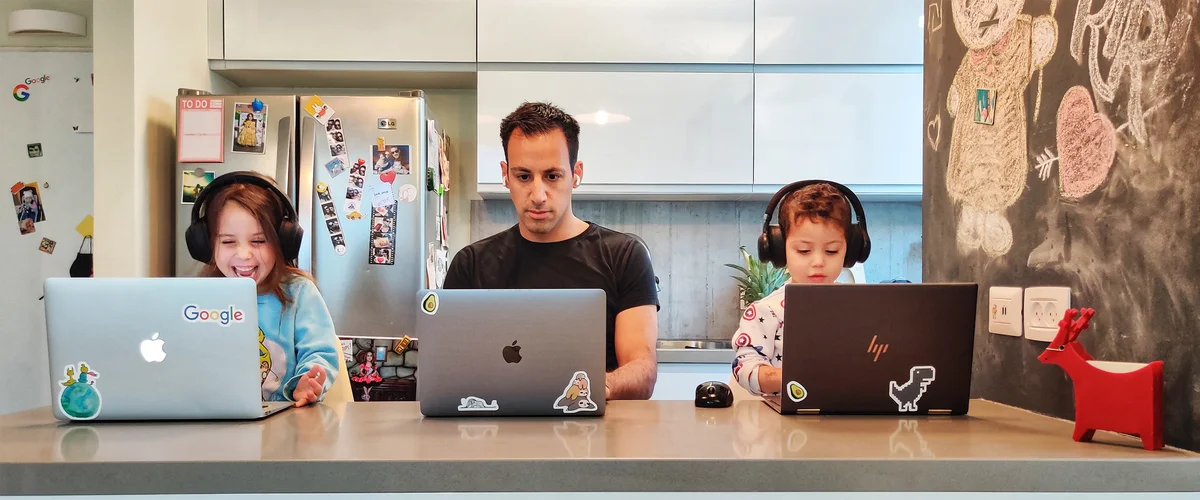 Asaf and his two kids all working at their laptops at the kitchen counter.