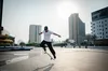 Skateboarder performing jumping trick in square in a city