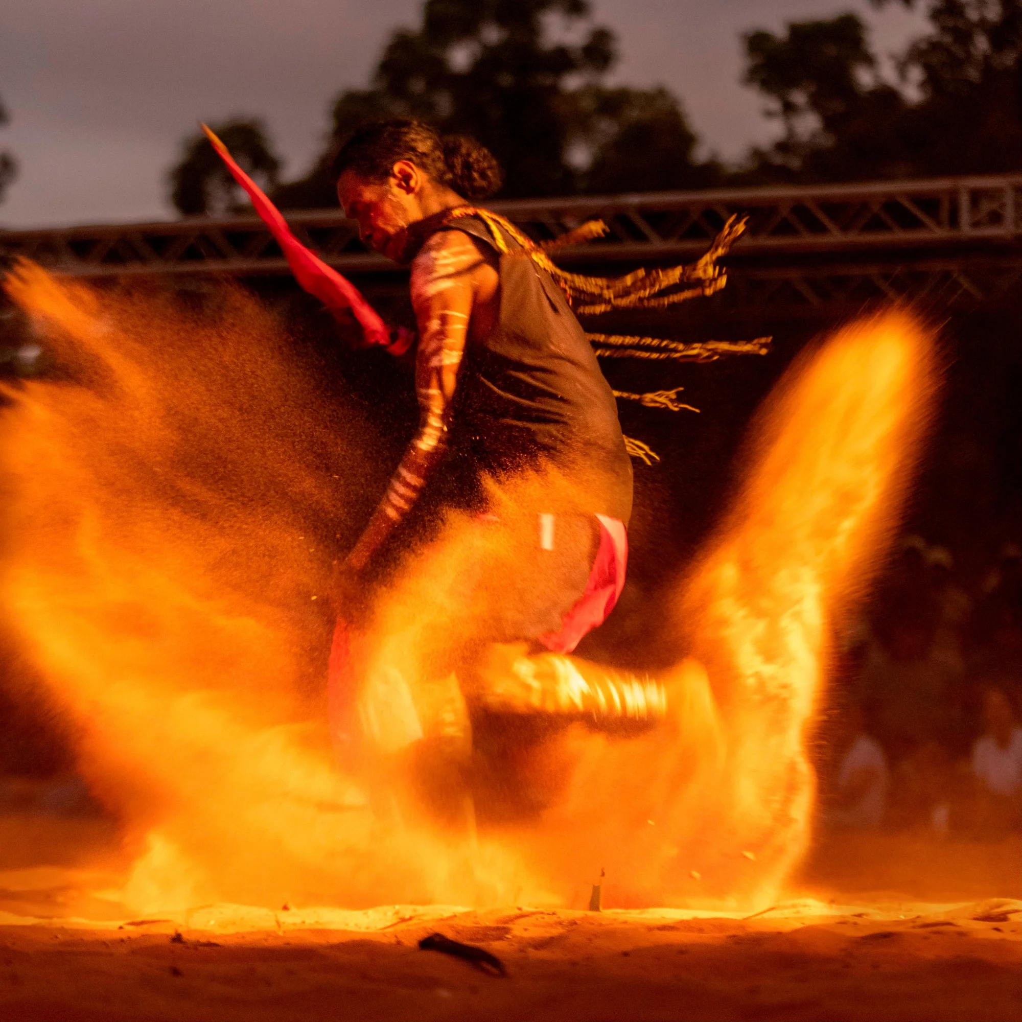 A man dances at Garma Festival at night, kicking up dirt