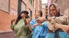 A group of three friends excitedly moving and dancing around outside on the street with Fitbit Inspire 3 on their wrists, tracking their activity every step of the way.