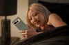 A woman looks at her Pixel phone while laying in bed.