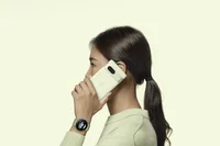 Image of a woman holding the new Pixel phone up to her ear and wearing a watch in a matching color