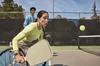 Woman in a wheelchair plays pickleball while wearing Charge 6 with a sport band.