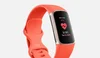 A Fitbit Charge 6 with a coral-red wristband. The screen shows the ECG app in use and shows a heart icon and the words “30 sec, tap to start.”