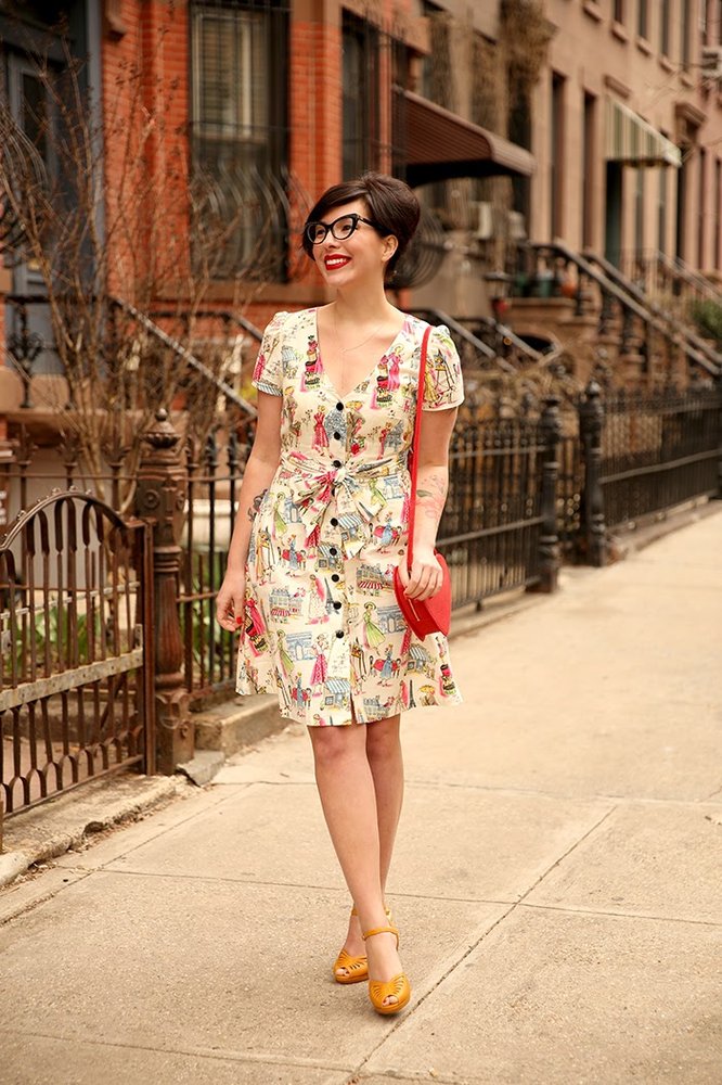 Keiko wears a patterned dress with a handbag.