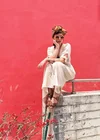 A woman sits on a cement ledge before a red wall.