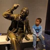 Landon seated next to a bronze statue of Albert Einstein