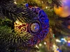 Image showing a macro shot of an ornament hanging in a tree. The lights are low and there is decorative lighting, but the ornament remains in focus while the background is blurry.