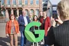 Menschen auf Marktplatz hinter einem grünen G als Google-Logo, rechts eine Frau von hinten, die mit einem Smartphone telefoniert