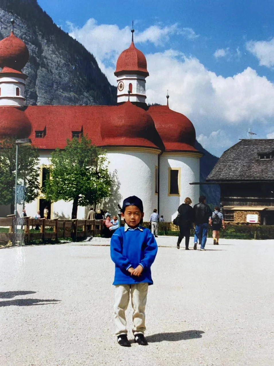 Marco Xu steht als 6-jähriger Junge vor der Wallfahrtskirche St. Bartholomä in Bayern.