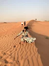 Neha Malhotra in sand in a dessert with an arm outstretched to touch the sand