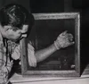 A man with his arm in an enclosed box full of bugs.