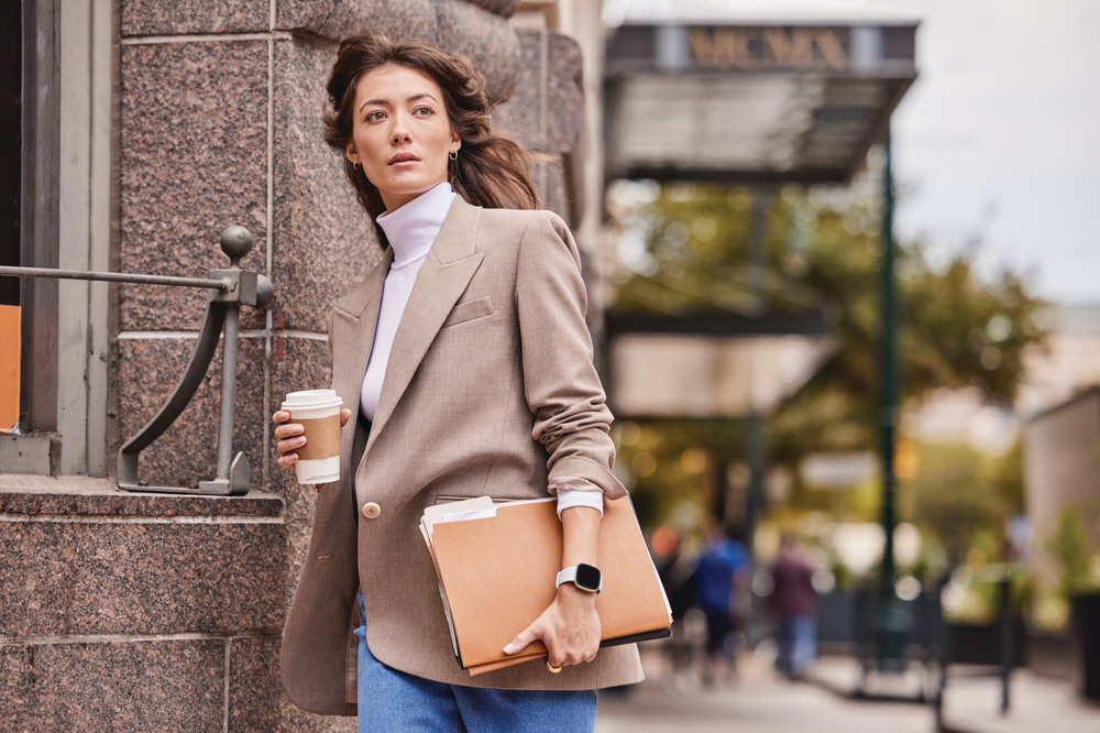 A woman walks to the office, carrying her work materials and wearing her Sense 2.