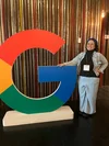 Sabrina Raimundo, mulher, branca, posa para foto ao lado de logo do Google.