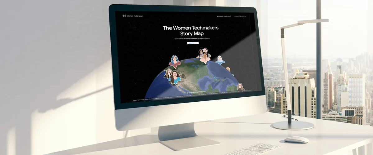 White desktop set sits on a white desk featuring a screen with a globe and several caricature images of women reading “The Women Techmakers Story Map.”