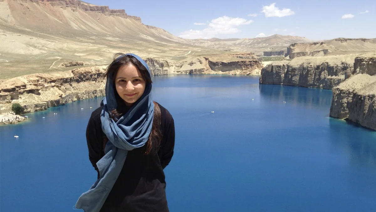 A photo of Shahla standing in front of a lake in Afghanistan.