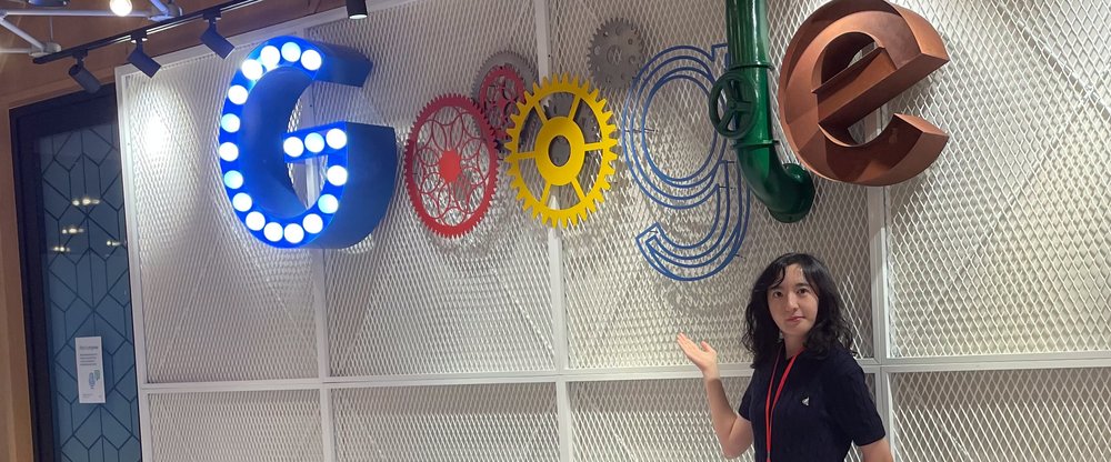 Sumin standing in front of a Google logo, made up of an assortment of industrial parts.