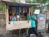 A merchant standing next to a stall on the side of the road in India, with signs indicating that he accepts Google Pay as a payment method.