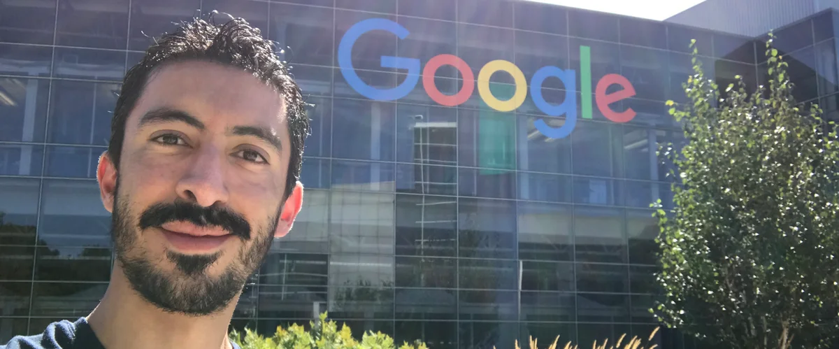 Ernesto is wearing a dark blue shirt and is smiling in front of a Google logo at our Mountain View headquarters.