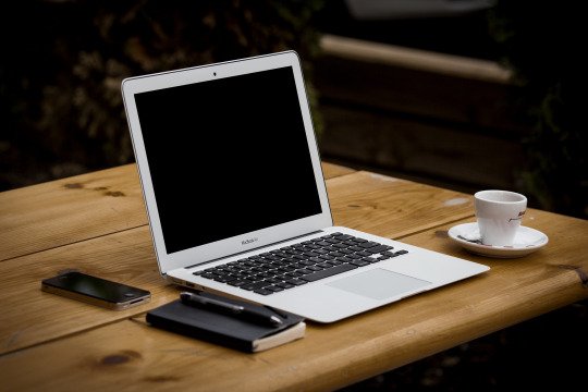 A photo of a laptop and coffee cup on a desk.