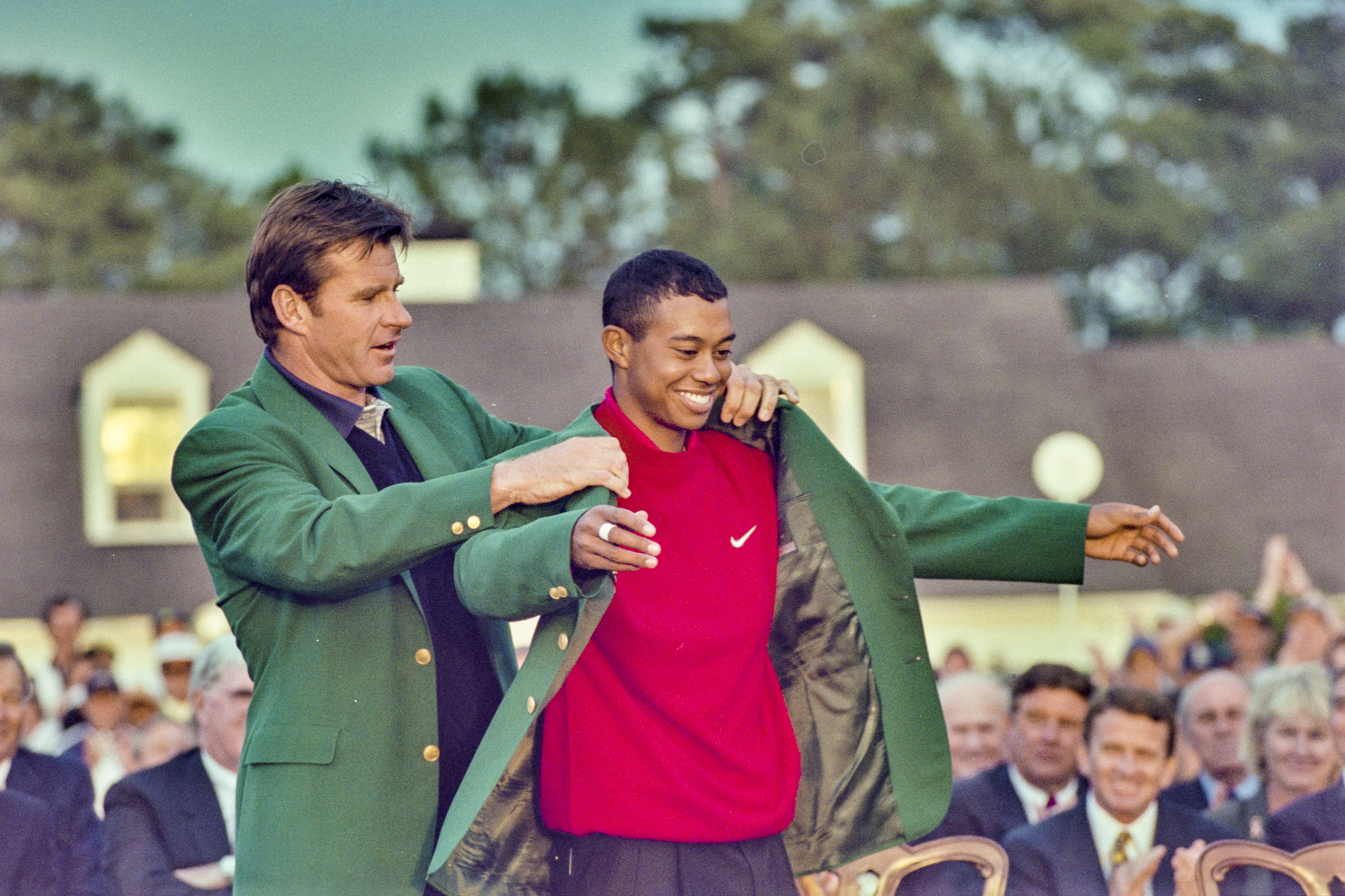 Tiger Woods being presented with the green jacket for winning a major golf tournament.
