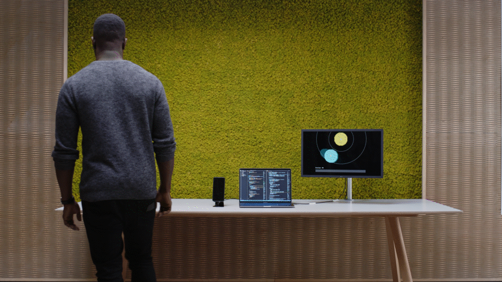 A man moves close to a computer screen that is recognizing his proximity and displaying it as fields on radar.