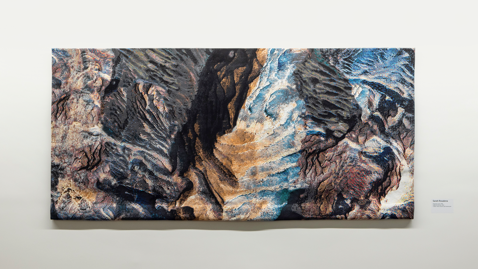 Abstract textile landscape: black, brown, blue, tan textures and deep ridges.