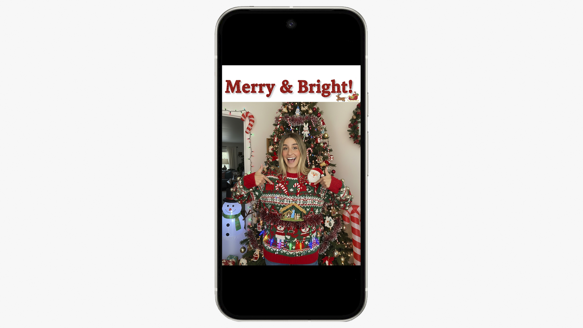 A smartphone displays a photo of the woman from the previous image, now wearing a festive red Christmas sweater and holding a mug, standing in front of a decorated Christmas tree and a small snowman decoration. The words Merry & Bright! are overlaid at the top.