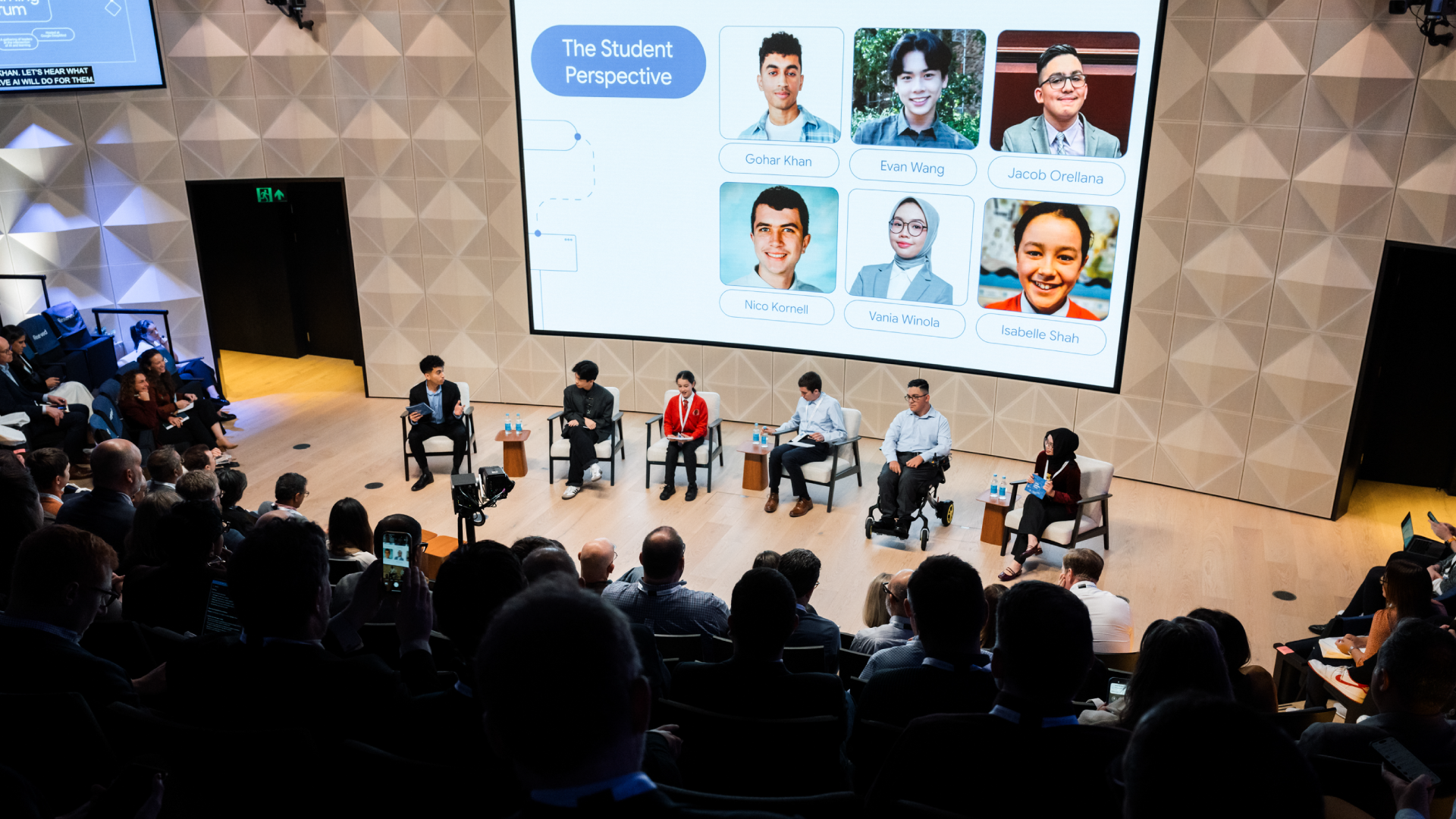 A panel of six students sits on stage beneath a large screen titled "The Student Perspective," displaying their names and photos.