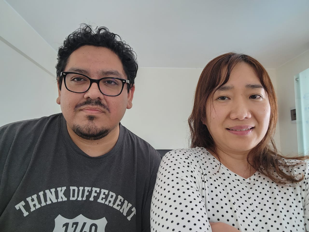 Two people stand side-by-side in an office and smile at the camera.