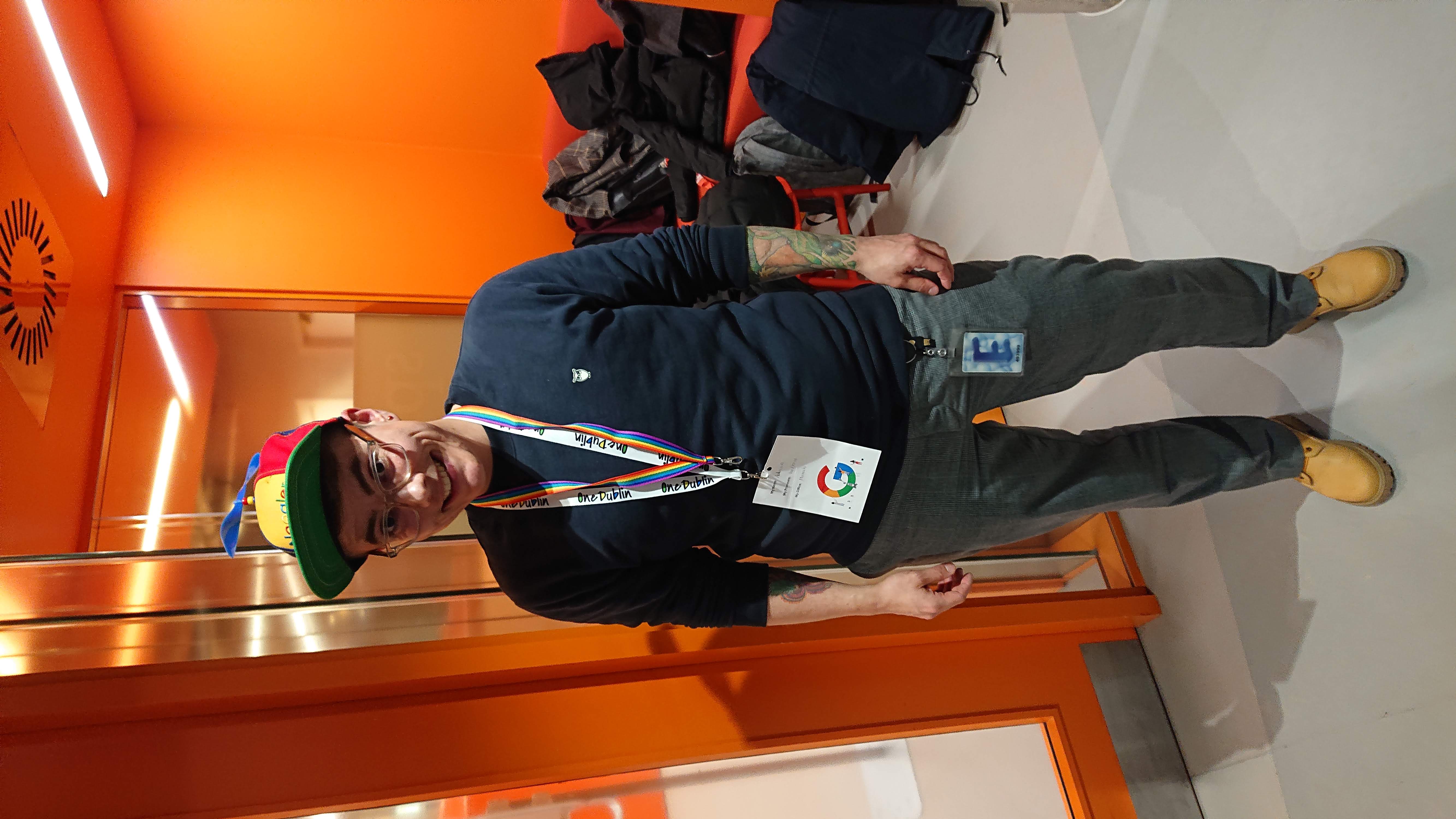 Adrian Hausner steht in einem Flur im Dubliner Google-Büro und trägt eine bunte Noogler-Mütze