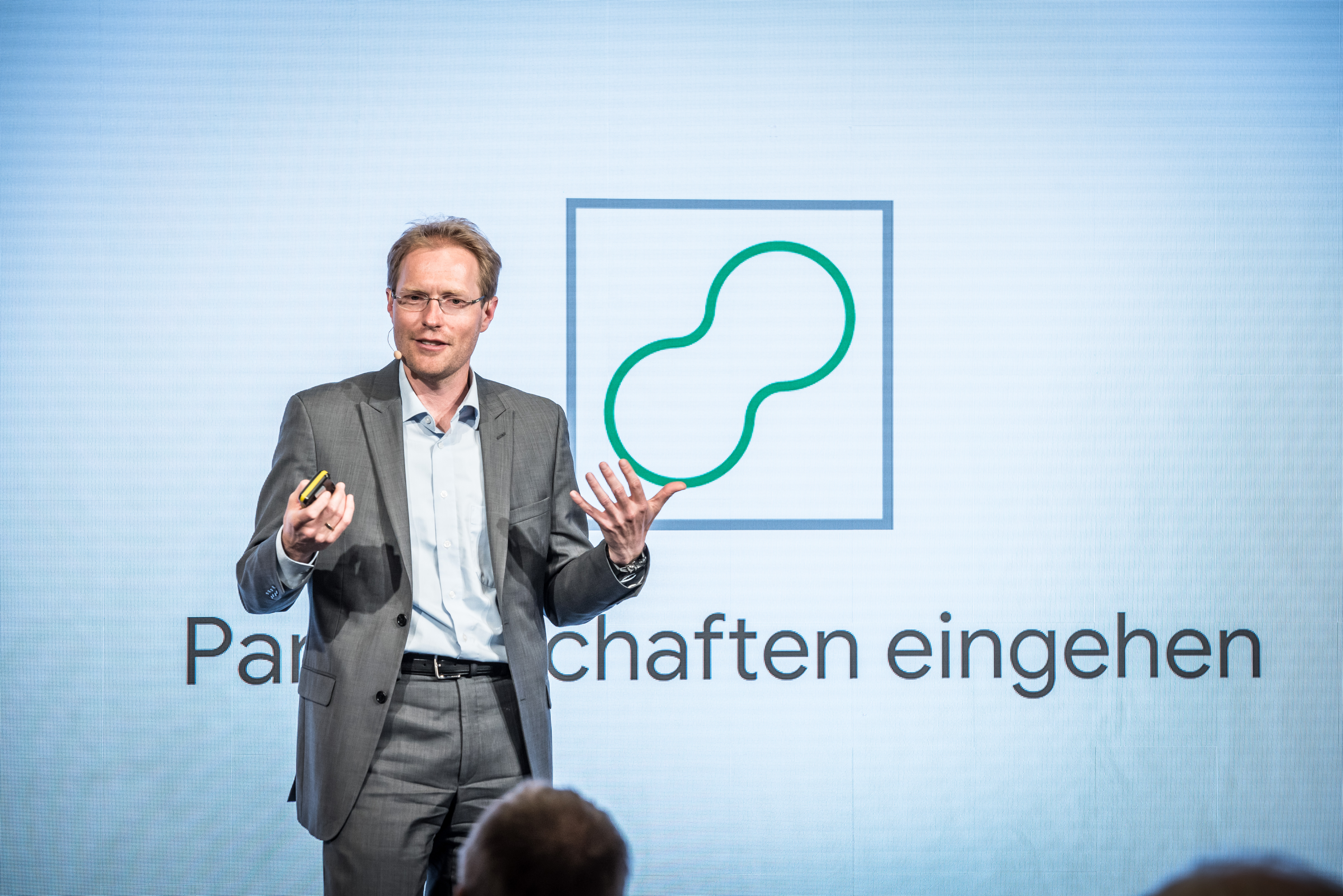 Das Bild zeigt Stephan Micklitz auf einer Bühne bei einem Vortrag