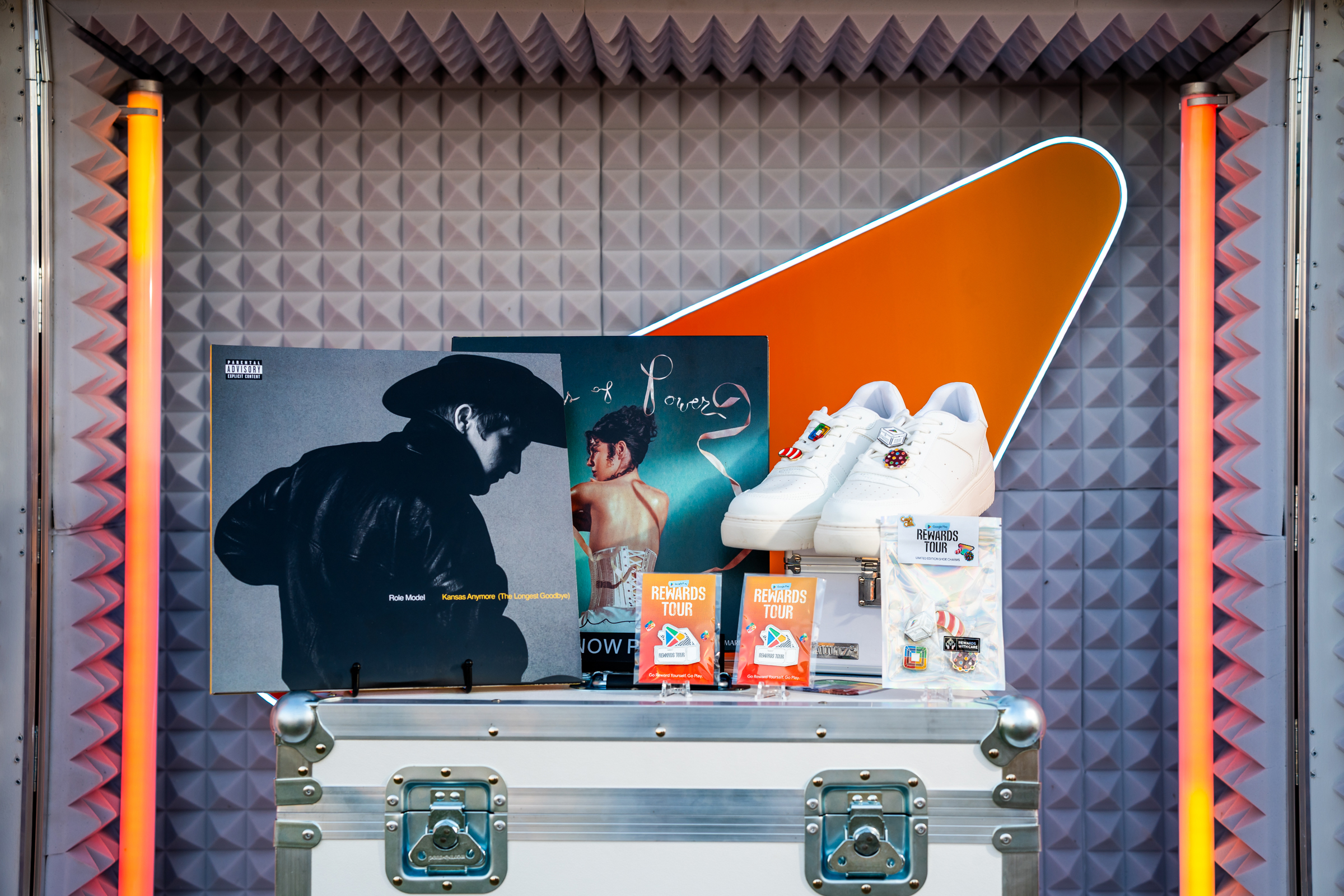 Two records, pins, sneakers, and stickers sitting on top of a roadcase