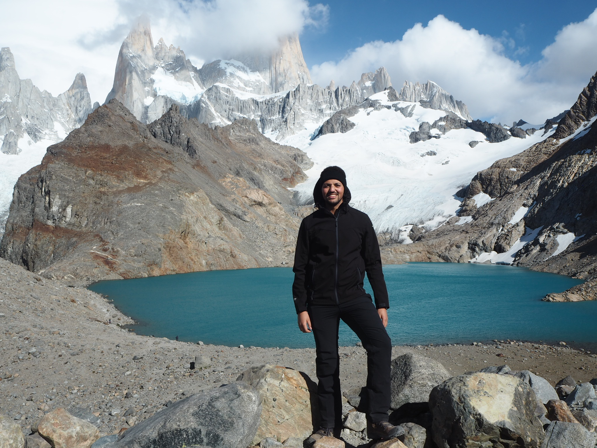 Bilal Essafi steht im sonnigen Patagonien vor einem See. Im Hintergrund ein Bergpanorama.