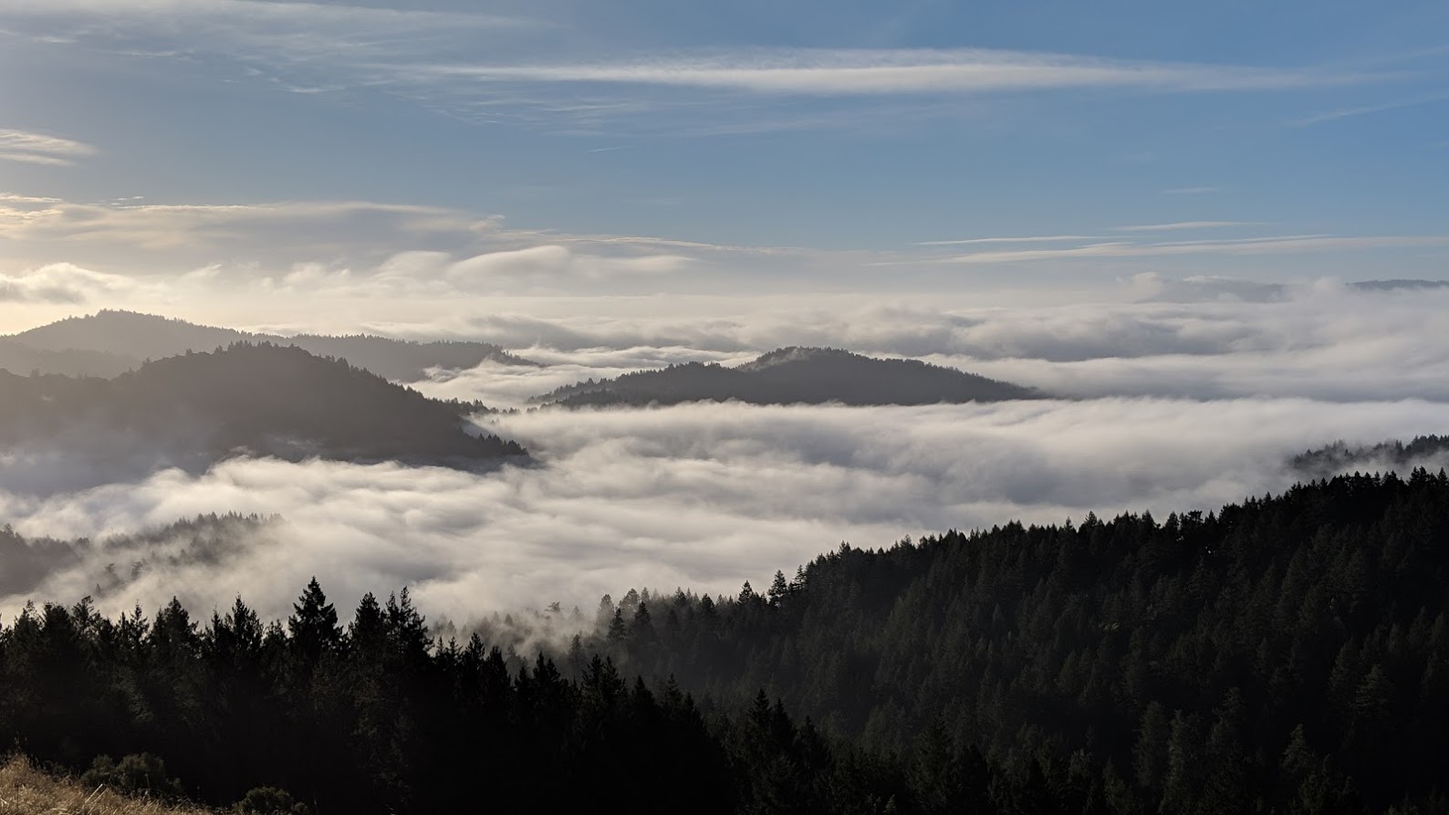 Photo showing clouds surrounding hilltops.