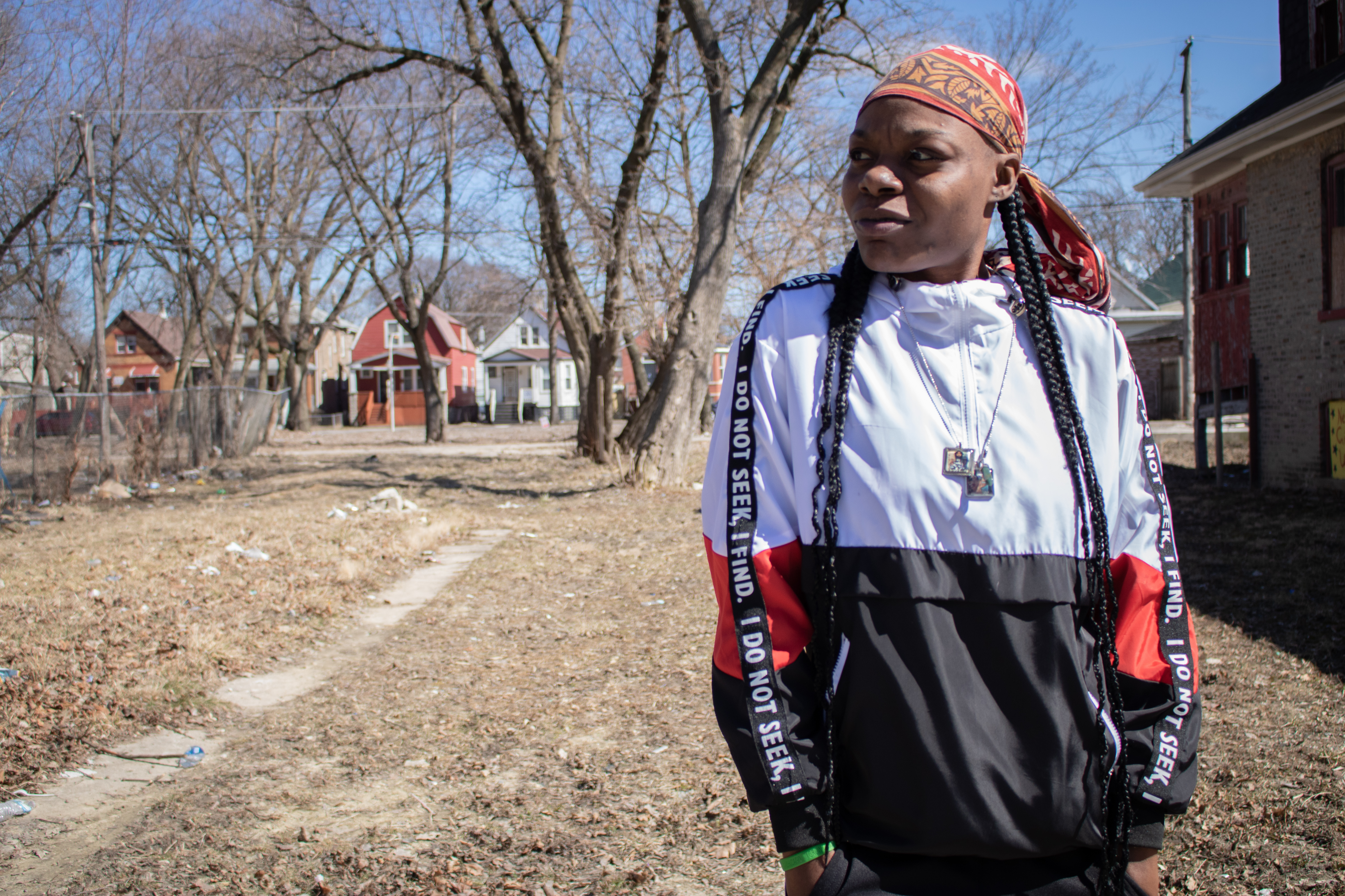 Marquita "Cece" Dixon stands in front of a vacant lot. Her grandmother used to own property next to the lot, but it is also now boarded up.