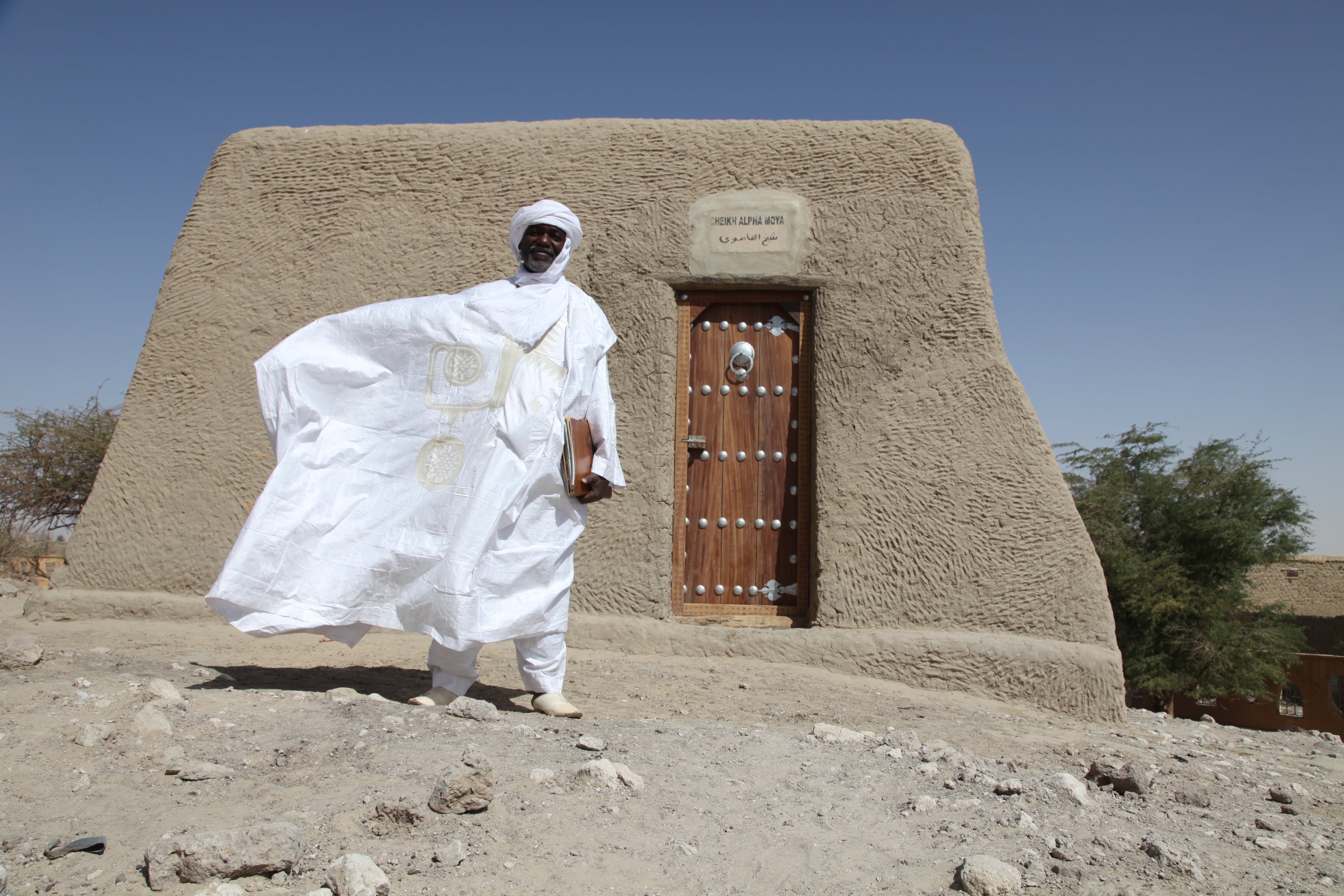 A Malian mason in front of a reconstructed ancestral tomb site.