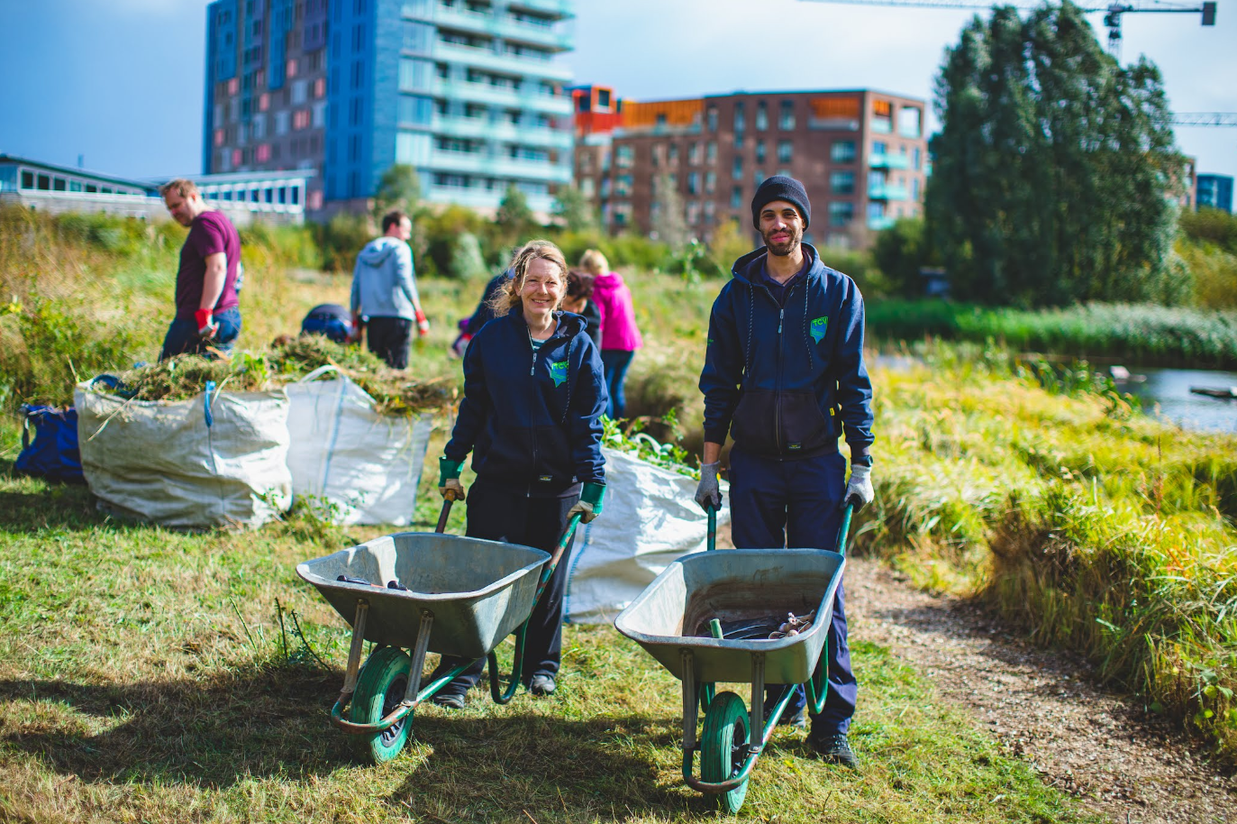 A picture of a group of conservation volunteers in London holding wheelbarrows by a wetland